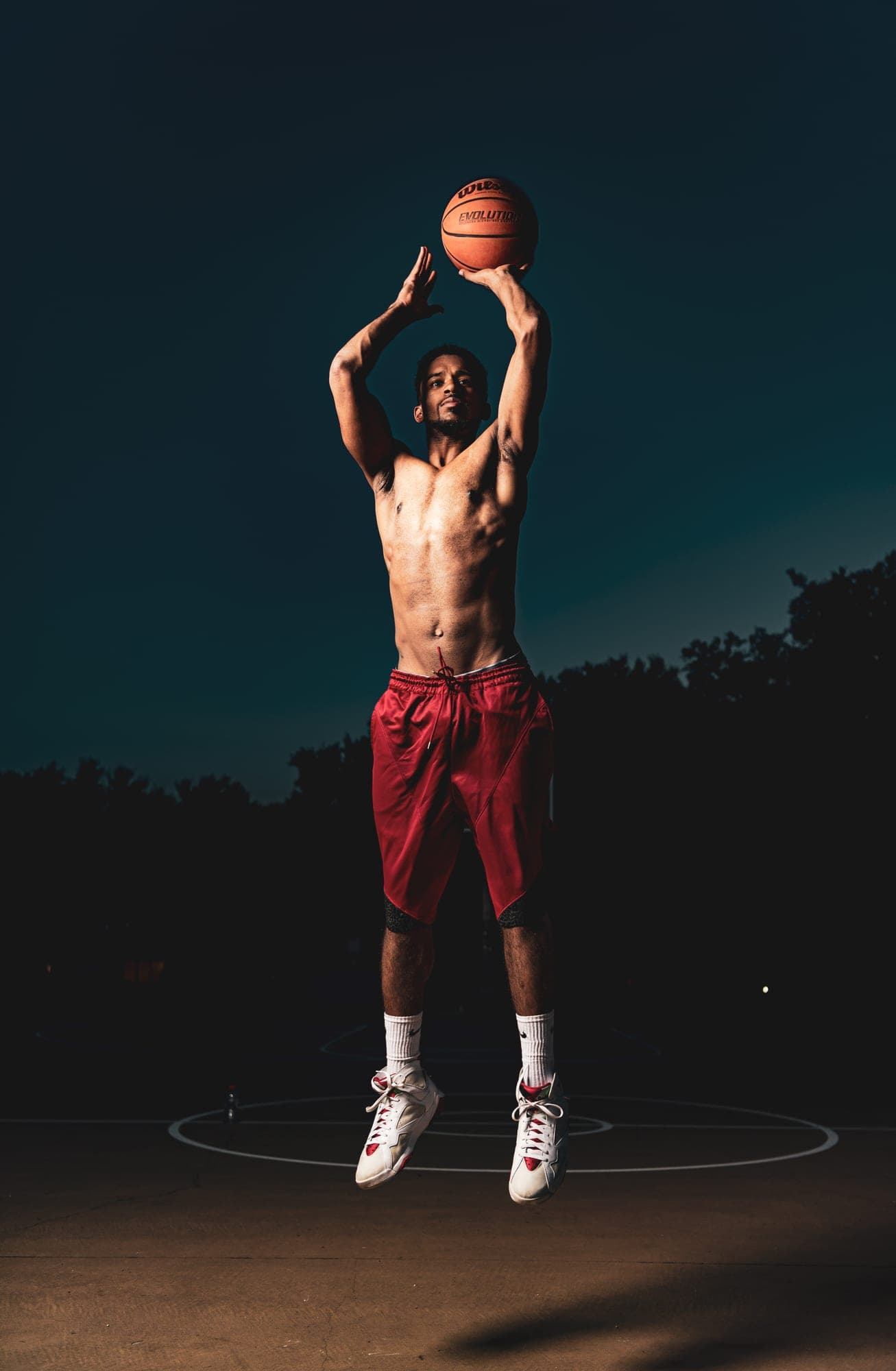 Abyon Ausar shooting a basketball on an outdoor court against a night sky