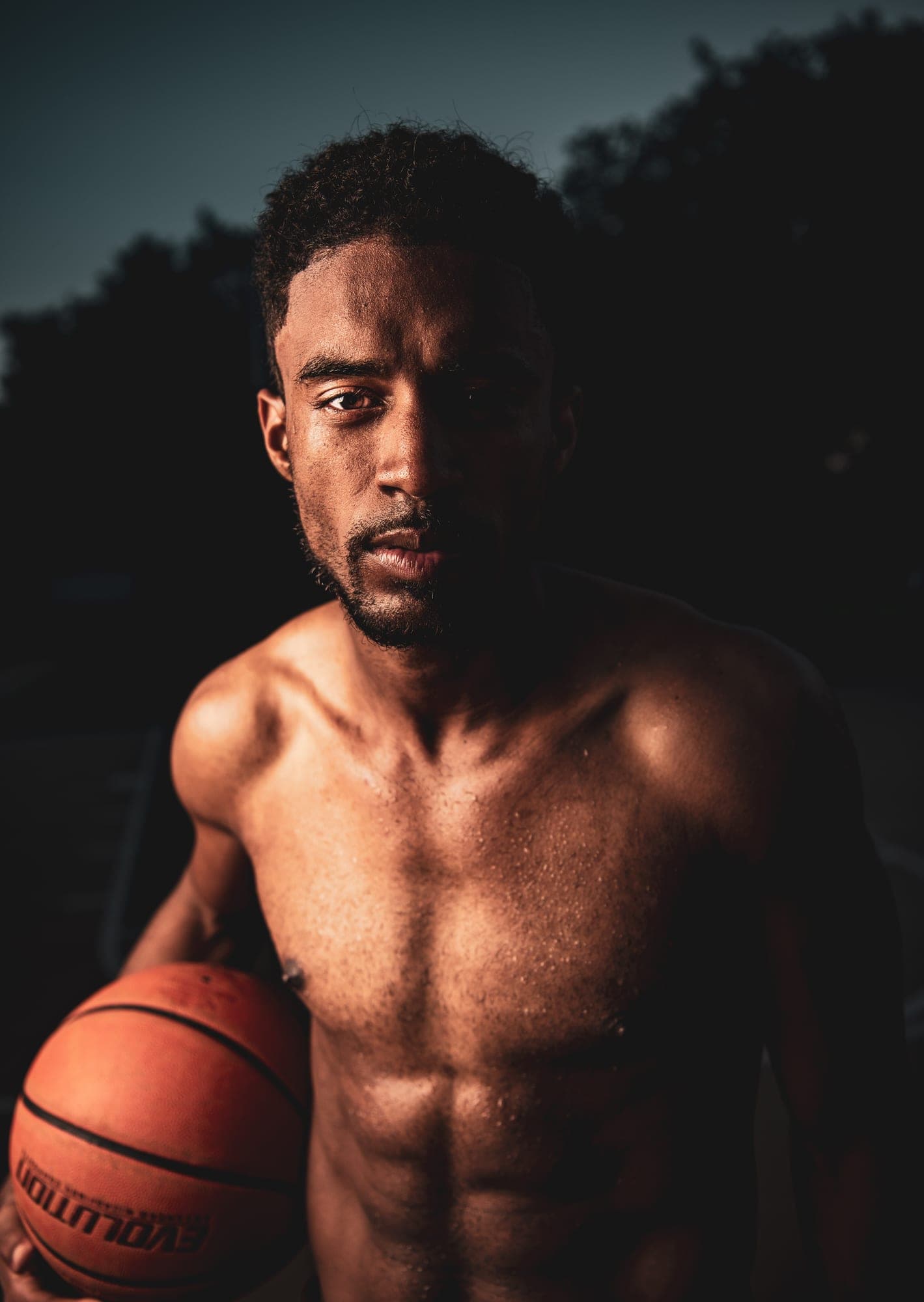 Close portrait of Abyon Ausar holding a basketball under hard directional light