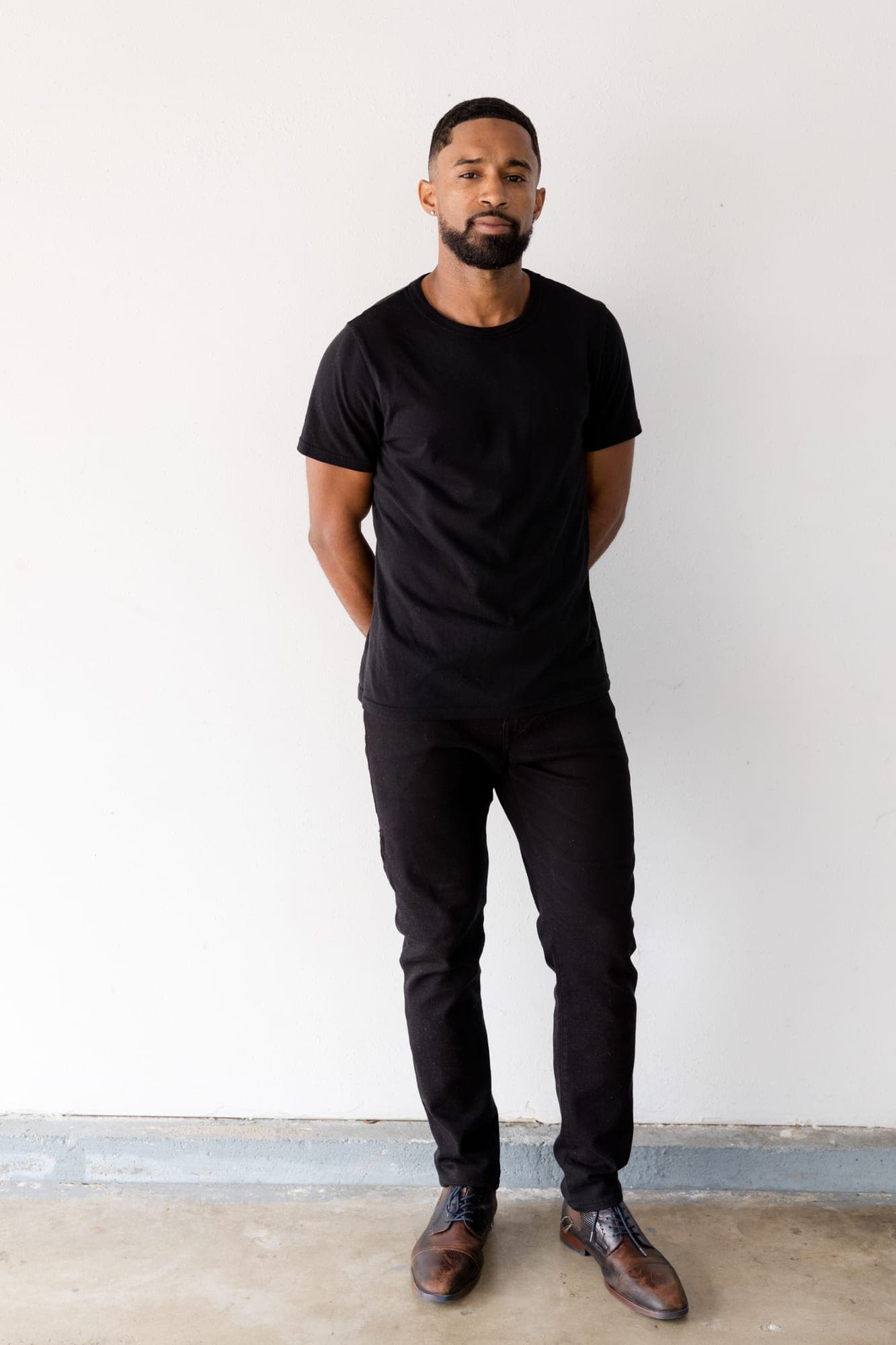 Full length digital of Abyon Ausar, hands behind his back, against a white wall